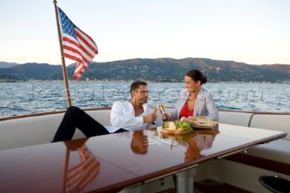 Lifestyle couple having drinks and coctails onboard a Vicem 72 classic motor yacht in the sunset Model Released.