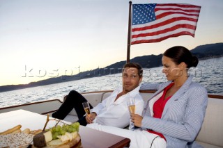 Lifestyle couple having drinks and coctails onboard a Vicem 72 classic motor yacht in the sunset Model Released.