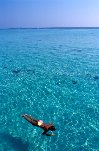 Girl female snorkelling on turquoise blue water in the Maldives