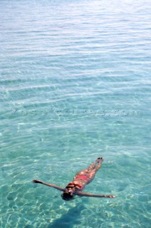 Girl relaxing lying floating on the surface of the turquoise sea water in the Maldives