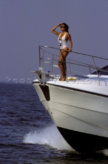 Sexy girl female model in white swimsuit onboard powerboat