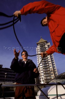 Two crew of a motorboat coiling the mooring lines in the city of London - Chelsea Harbour