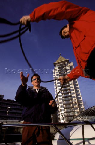 Two crew of a motorboat coiling the mooring lines in the city of London  Chelsea Harbour