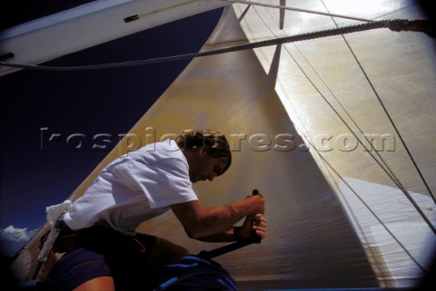 Crew member trimming sail on winch 