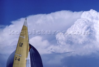 Sailor climbing aloft into dramatic skyline on 12 metre yacht