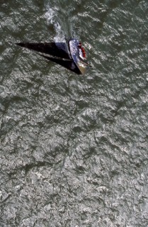 Aerial shot of racing yacht casting shadow over water
