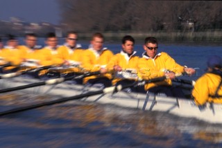 A team of rowers wearing yellow uniform clothing  in a skull on the River Thames