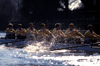 A team of rowers wearing yellow uniform clothing  in a skull on the River Thames