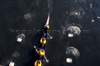 A team of rowers wearing yellow uniform clothing  in a skull on the River Thames