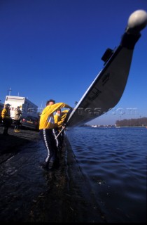 A team of rowers wearing yellow uniform clothing  in a skull on the River Thames