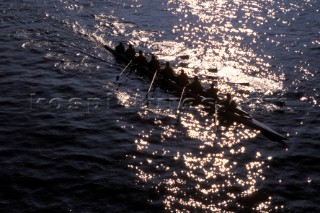 A team of rowers wearing yellow uniform clothing  in a skull on the River Thames