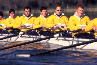 A team of rowers wearing yellow uniform clothing  in a skull on the River Thames