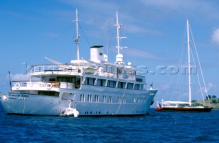 A large sailing yacht is drawfed by a huge super yacht in an anchorage in St Maarten, Caribbean