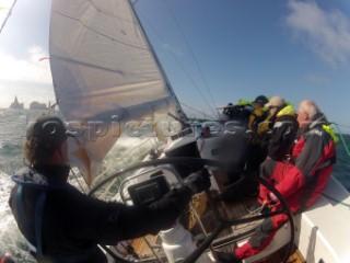 Helmsman driving upwind in rough seas onboard the Norwegian J133 Madjus during the JP Morgan Round the Island Race 2012 by The Needles