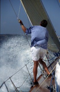 Close up of a man standing on a boat and holding a rope.