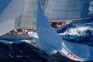 The crew of the giant 182ft schooner Adela, owned by American George Lindemann, demonstrates the commitment and technique reserved for only the most professional of crews. As the yacht changes course from a run downwind onto a reach, there is a need to reduce sail. The crewmember controlling the spinnaker halyard uses precise judgement in controlling the drop of the 1000 sq metre sail at the same rate as the crew is gathering it in onto the deck. The skill is making the giant sail hover across the water allowing wind to still pass under it. Just a few metres too much halyard released too quickly and the sail fills with water stopping the 350 ton yacht and potentially breaking expensive sails, equipment, spars and members of her crew. Maxi Yacht Rolex Cup 2001. Porto Cervo, Sardinia.