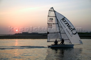 RS800 dinghy sailing under asymmetric spinnaker at sunset on the Hamble River, UK