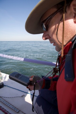 Male navigator using GPS to sail in a yacht race Round the Island Race on a J80 sportsboat