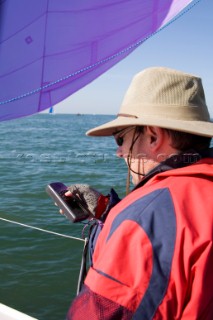 Male navigator using GPS to sail in a yacht race Round the Island Race on a J80 sportsboat