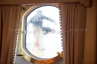 Crew seen through a porthole onboard superyacht Talitha