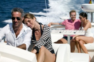 Four people sitting on top of yacht enjoying themselves.