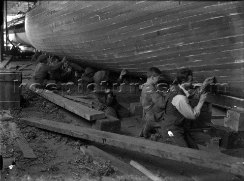 Caulking team work on a hull at Grove  Gutteridge yard in Cowes Isle of Wight in the 1930s