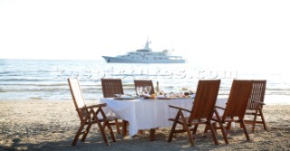 Dinner on the beach with superyacht White Cloud in the background