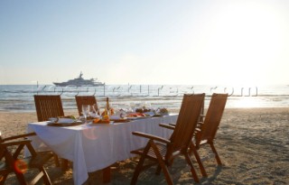 Dinner on the beach with superyacht White Cloud in the background