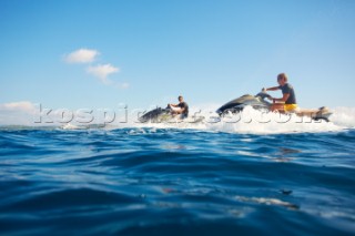 Two men jet skiing in the mediterranean sea.