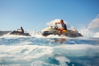 Two men jet skiing in the mediterranean sea.