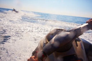 Two men jet skiing in the mediterranean sea.