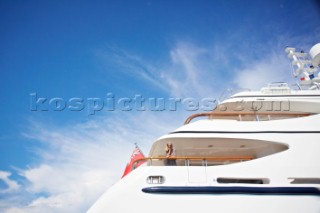 Side view of a superyacht in the mediterranean sea. Woman standing on deck  and leaning on railing looking at view