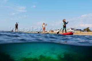 Two girls and a man paddleboarding