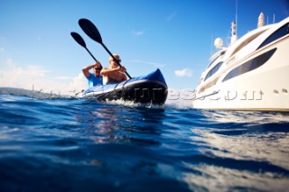 Couple kayaking near a superyacht