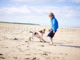 Boy playing with a dog on the beach