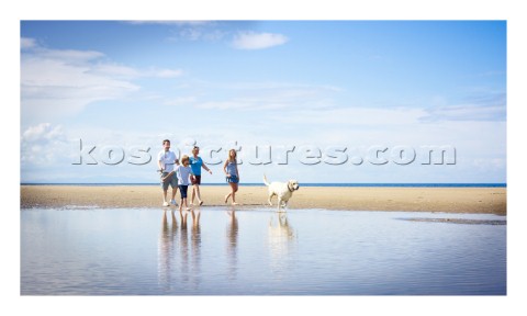 Family walking on the beach with a dog