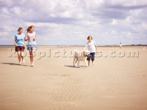 Family walking on the beach with a dog