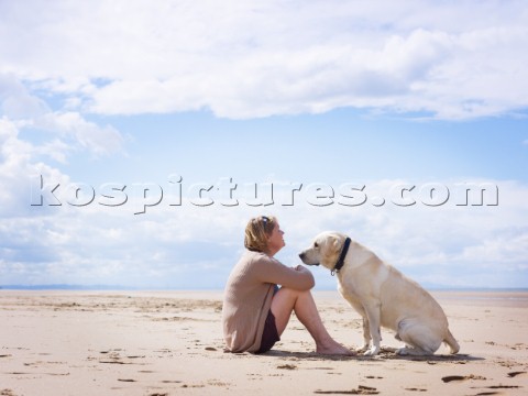 Woman sitting on beach with a dog