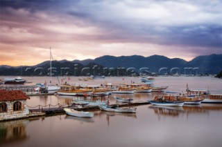 Boats fluttering the Turkish flag rest on calm waters before an approaching storm.