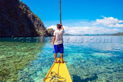 Filipino boatman navigating through a shallow reef at Hidden Lagoon Coron Island Palawan Philippines