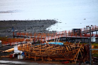 A traditional wooden fishing boat under construction on the Costnera of Puerto Williams.  The boat buiders work outside, with no cover, very simple hand tools & steam.  Puerto Williams, Isla Navarino - Chile