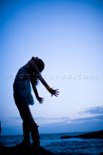 Silhouetted portrait of Stephanie Crocker with her arms back like wings standing on a rock over the ocean. Santa Cruz, California.