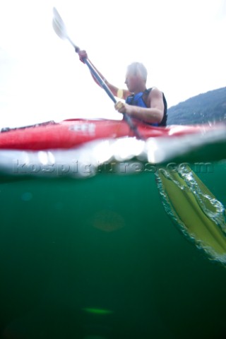 Over under water view of Patrick Orton paddling a sea kayak in Lake Pend Oreille near Sandpoint Idah