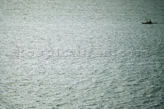 A lone sea kayaker paddles across the shimmering surface of Lake Pend Oreille in Sandpoint, Idaho