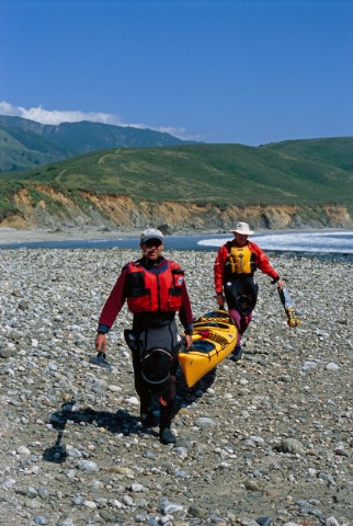 Writer Peter Heller and friend Landis Arnold portage their sea kayak along the beach at Andrew Moler