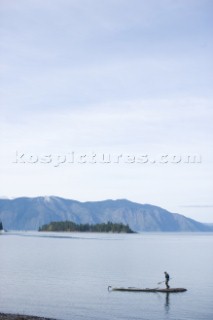 Woods Wheatcroft stops on a tiny rock island while sea kayaking on Lake Pend Oreille near Sandpoint, Idaho.