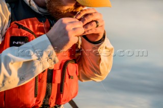 Fisherman ties on another lure at sunset