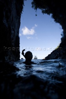 A cave diver looking out at a boat through an opening in the cave at the surface, in Cocos Island, Costa Rica.