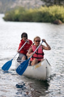 Two young women canoeing at Silver Lake near Kirkwood Mountain Resort, California.