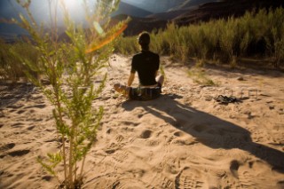 Elisa Friedman relaxing in the sand for the sunset while on a rafting trip down the Colorado River through the Grand Canyon, Arizona.